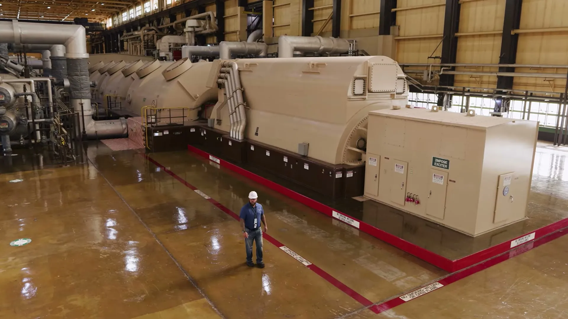 Generator and turbine line in the Braidwood turbine hall with a worker for scale